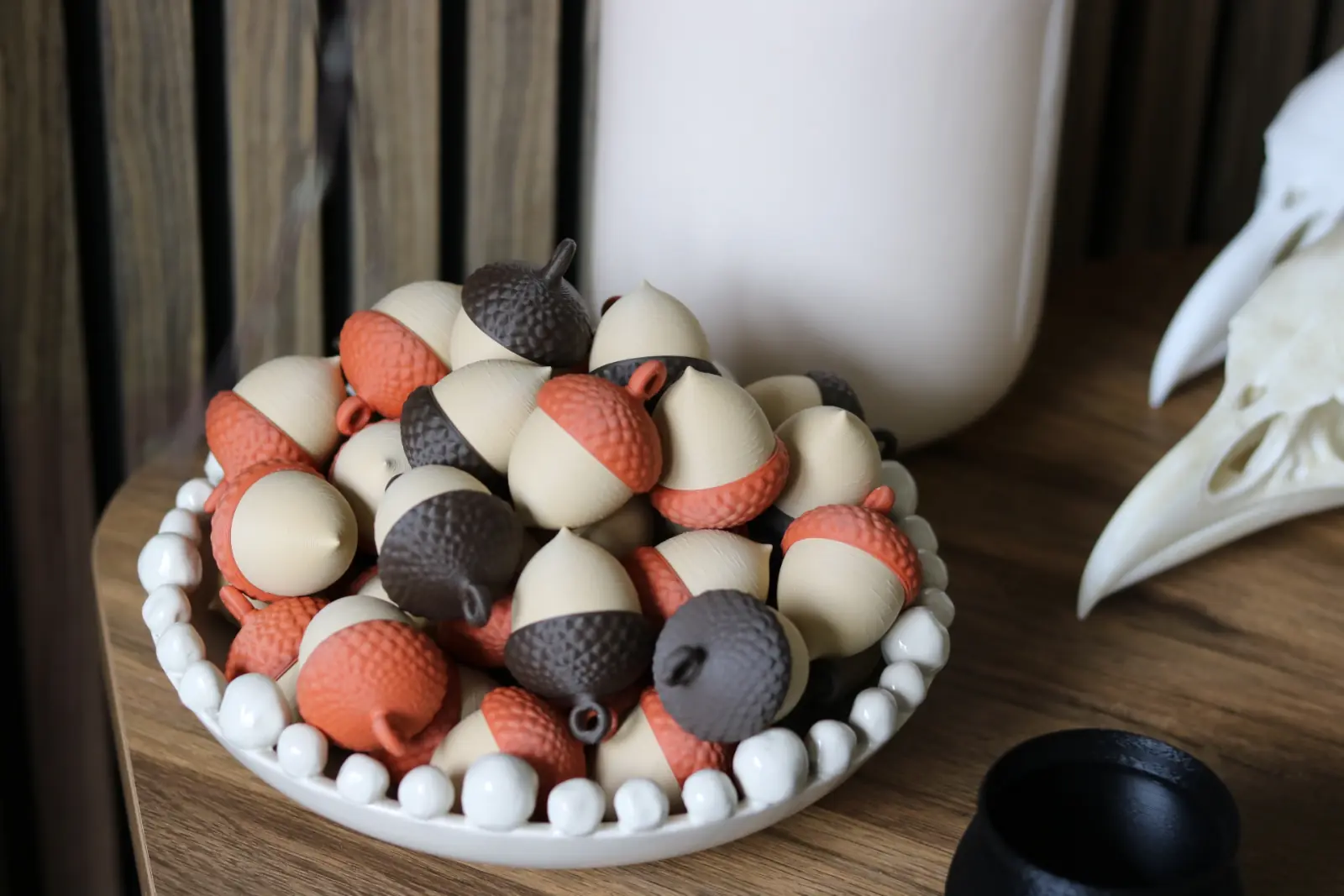 A bowl of cream, brown, and orange acorn ornaments.