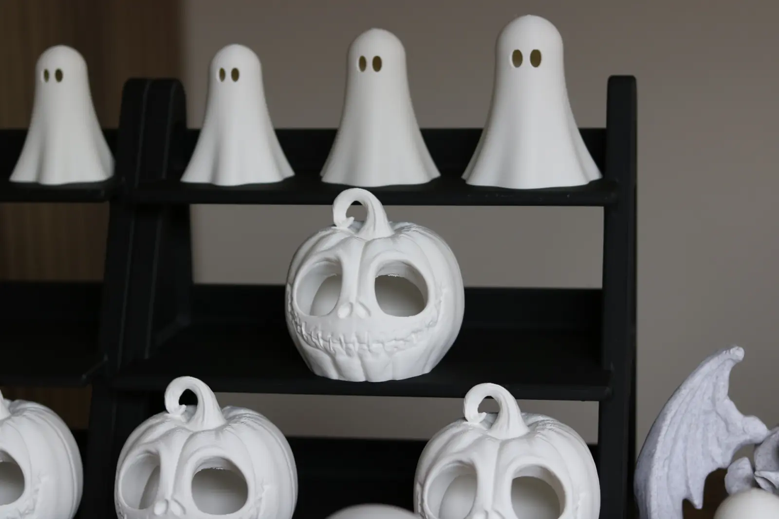 White ghost figures and pumpkin lanterns on a black shelf.